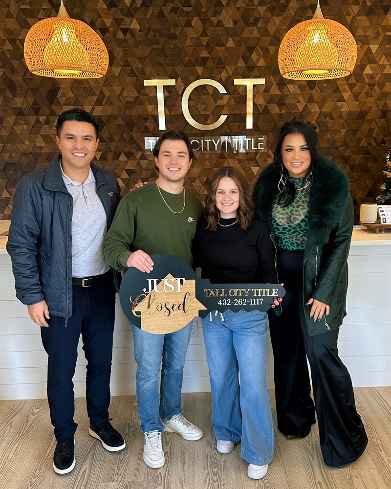 Perea Mortgage clients celebrating at the title company with a Just Closed sign